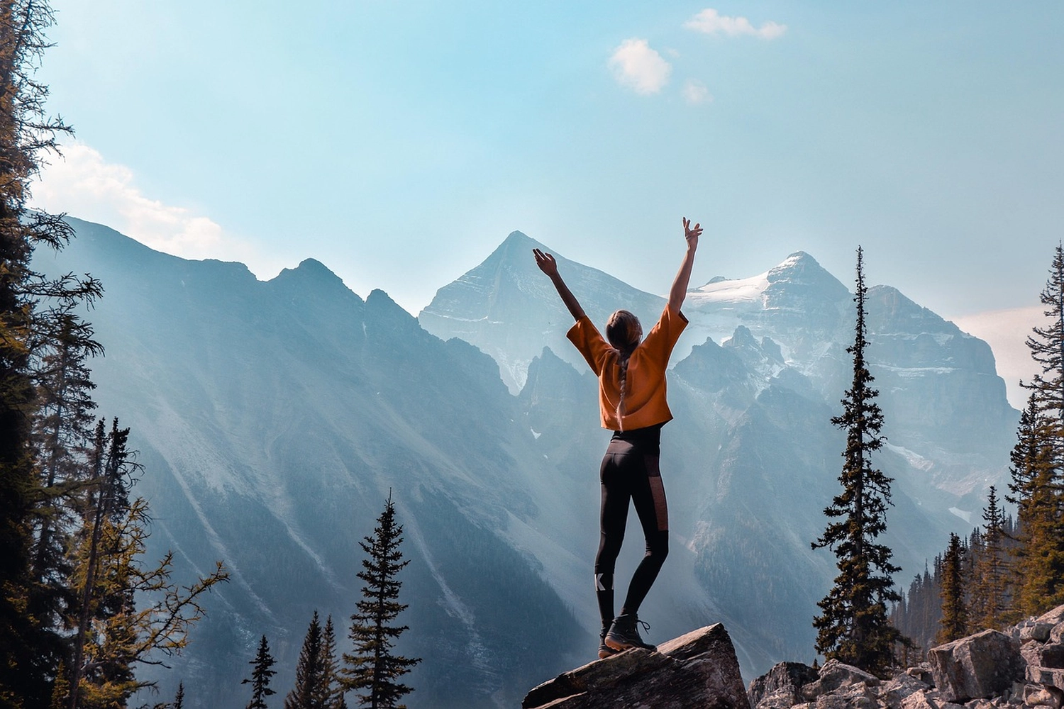 Mindtrail - Coaching und Mentoring - Eine Person mit erhobenen Armen steht auf einem Bergpfad.